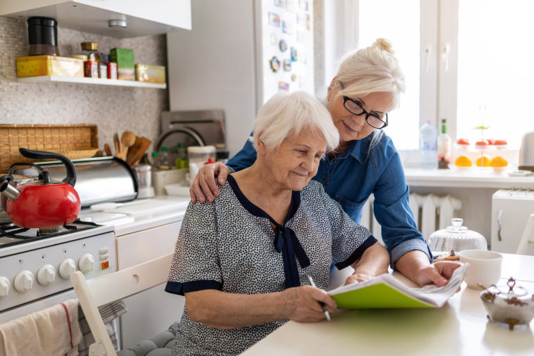 Caregiver helping senior with Alzheimers write in a notebook