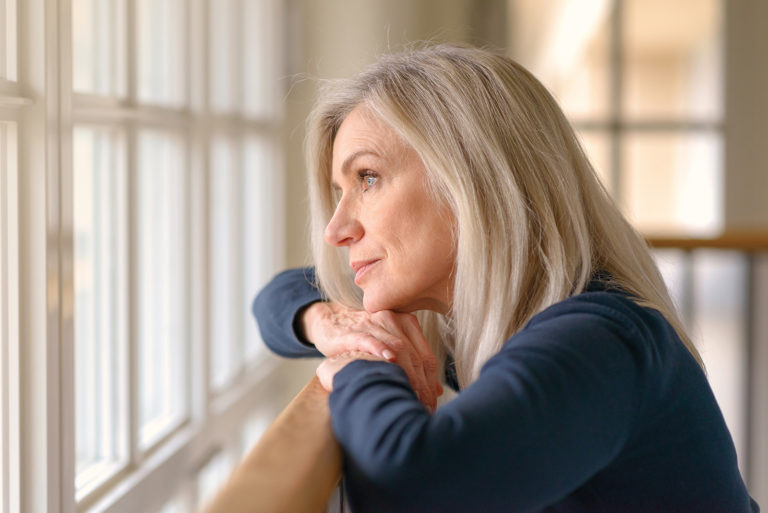 Senior woman looking out the window contemplating aging in place