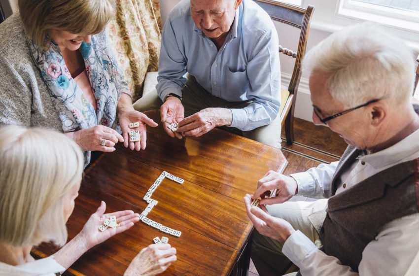 Group of senior friends are playing dominoes games at a table together.