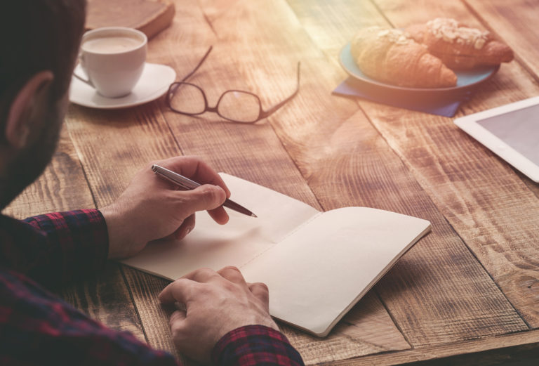 Man writing in a journal to ease caregiver stress