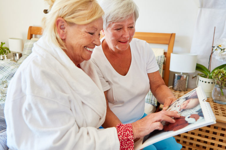 Elderly woman and adult daughter looking at photo memory calendar