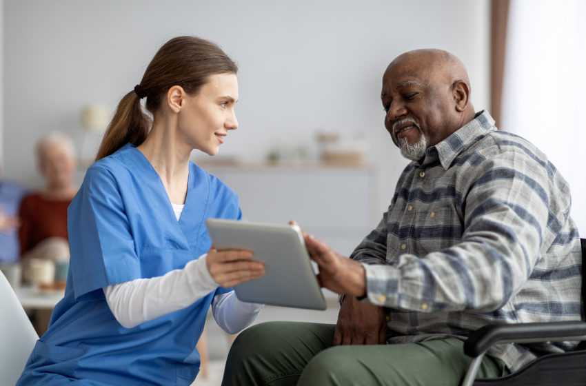 Nurse helping senior man use tablet for health apps