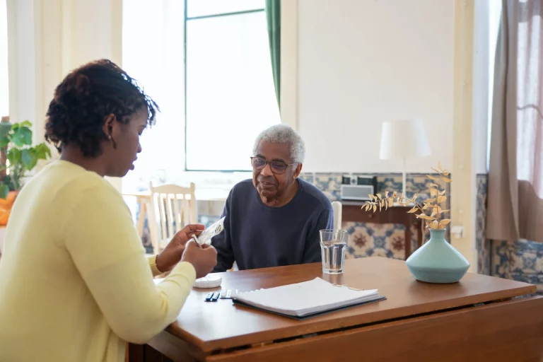 A woman in a yellow sweater talks with an older man in a dark sweater.