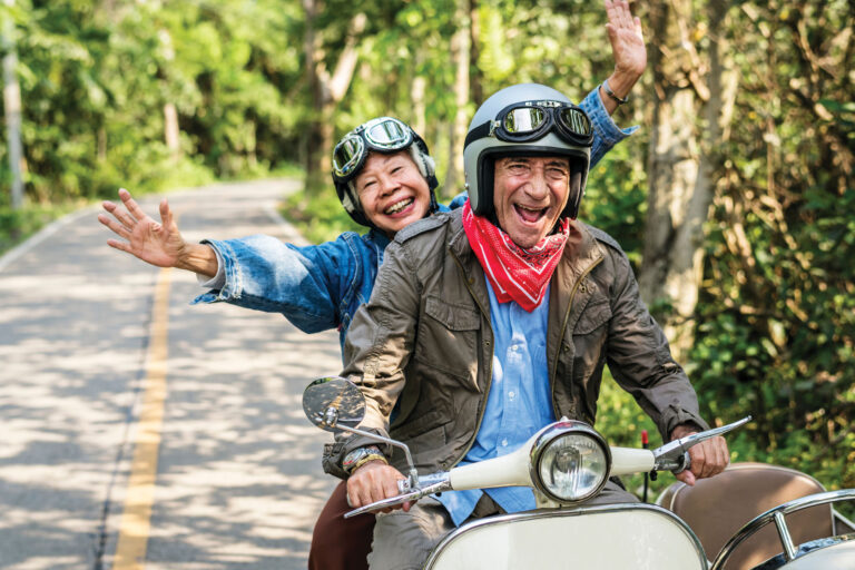 Two seniors on a winding road on a scooter expressing the joy of travel