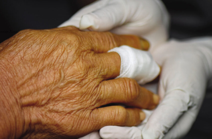 Hand of a senior woman with a bandage around her finger showing wound care
