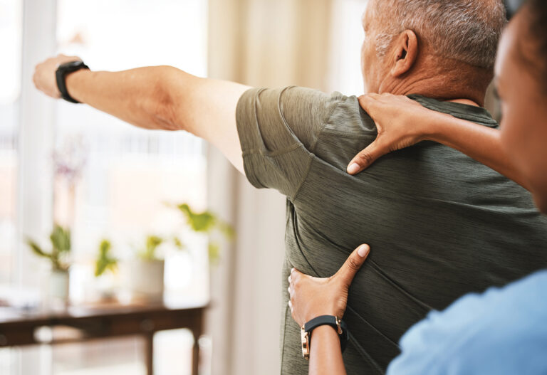 In home fitness. Trainer working with senior man in his home.