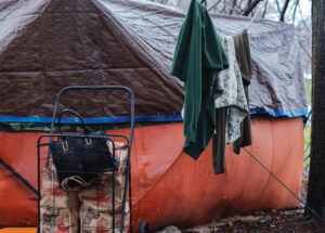 Women and homelessness. Photo of a purse inside a cart in front of a tent.