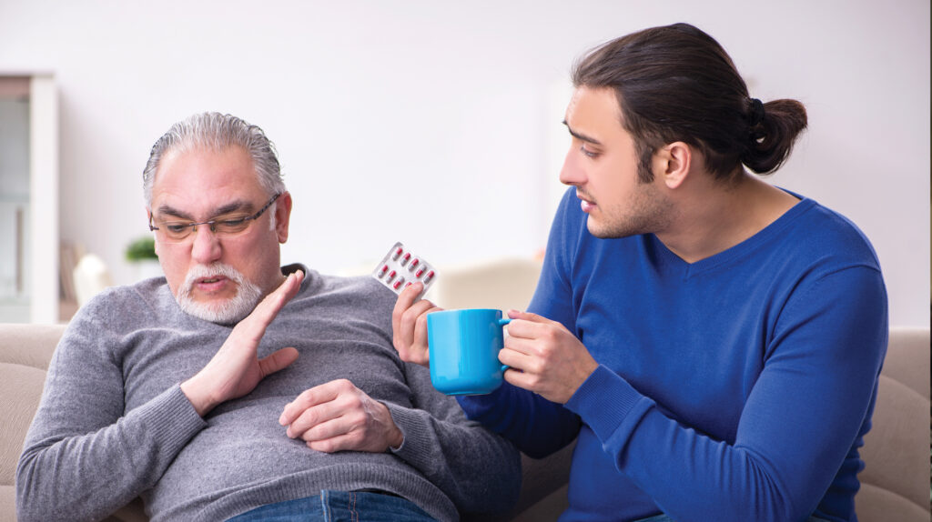 Son cares for resistant father, showing noncompliant care recipient