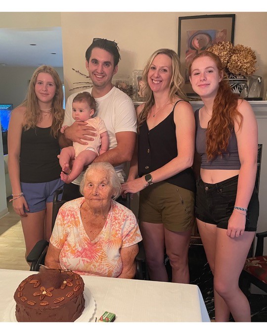 A family gathers around a grandmother and her birthday cake for her 100th birthday