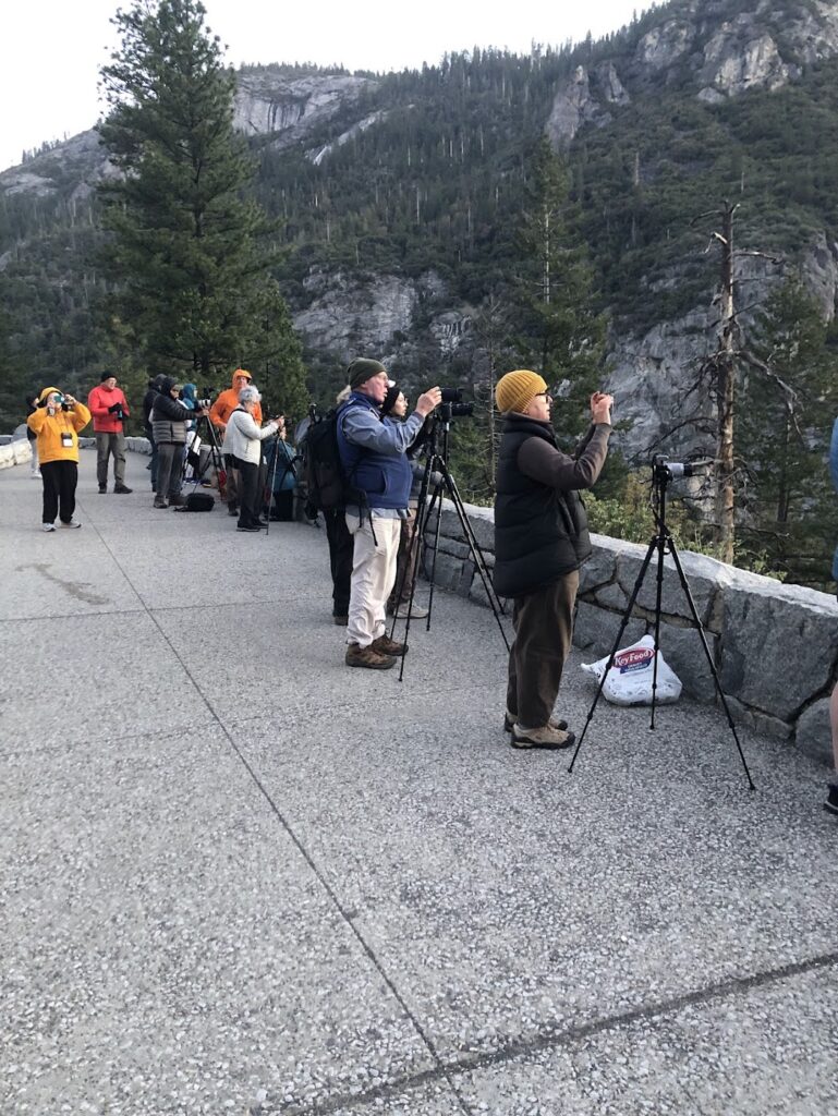 A group of travel photographers set up their tripods at an overlook in Yosemite National Park