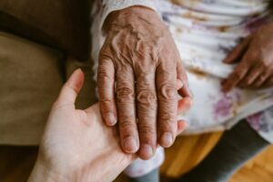 A younger hand holding a wrinkled, older hand.