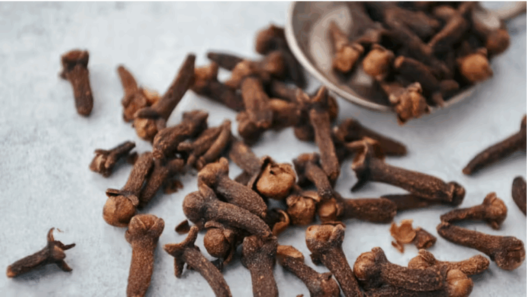 A pile of cloves spill out of a dish and onto a table.