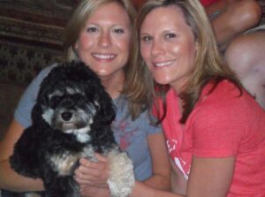 Sarah Rasby and her twin sister pose with their dog.