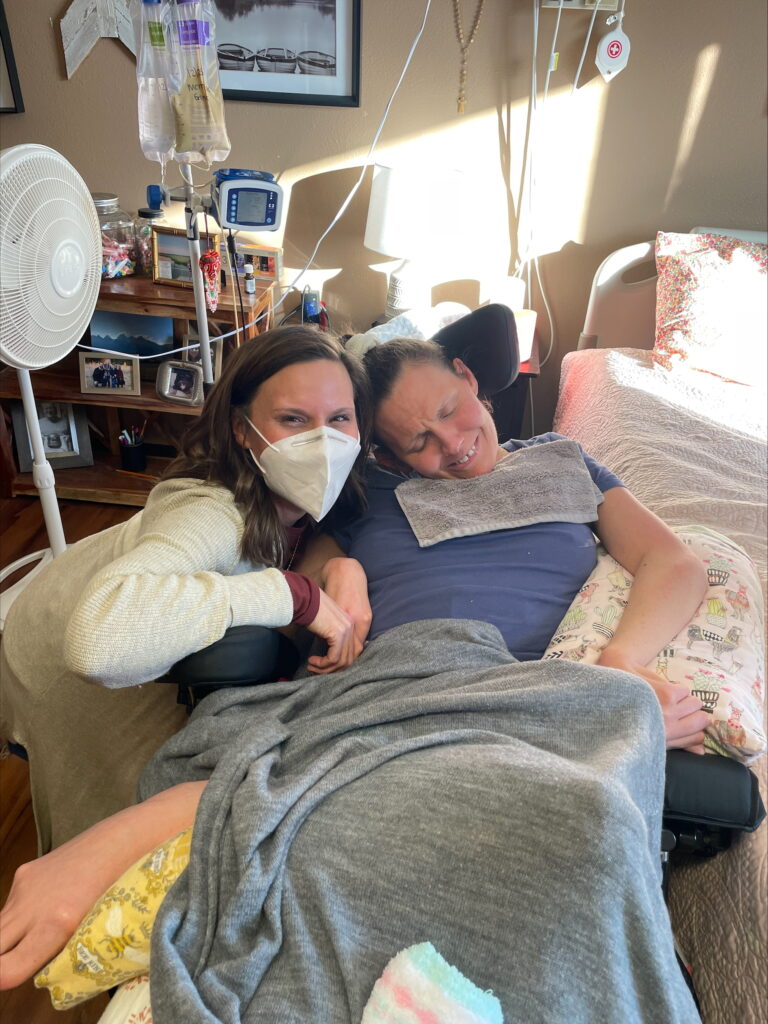 Sarah Rasby, wearing a hospital mask, poses with her sister in a hospital room.