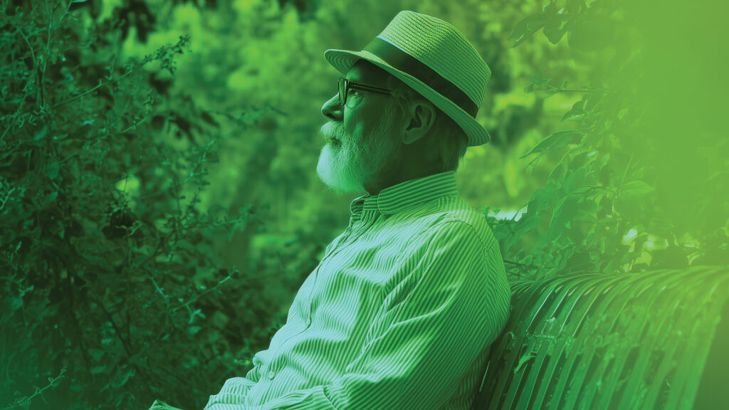 Senior man sitting in green garden setting. Biophilia.
