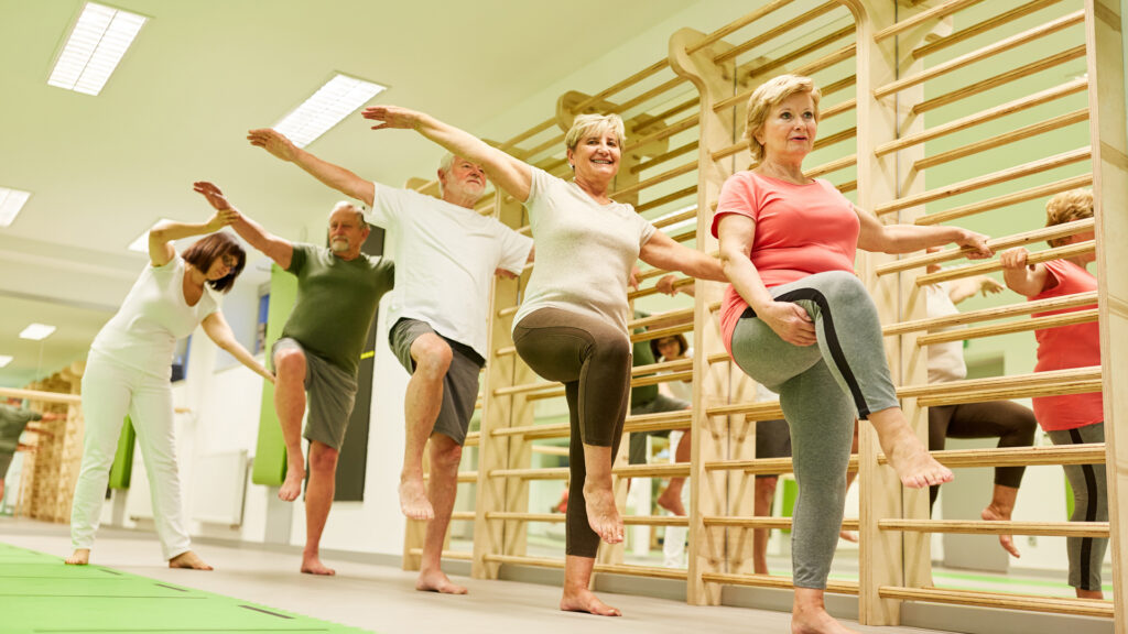 Seniors practicing balance exercises in a group fitness class.