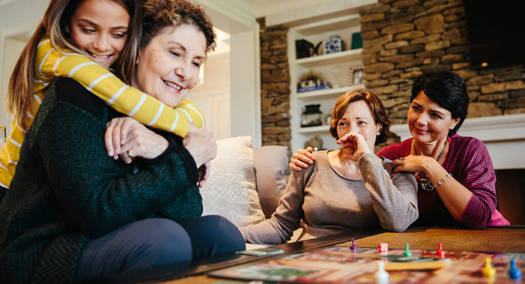 A family plays a board game with a senior woman