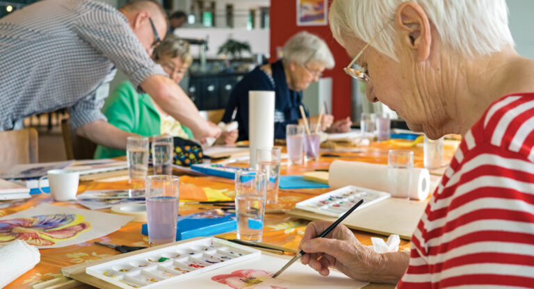 Senior woman seen painting in a classroom